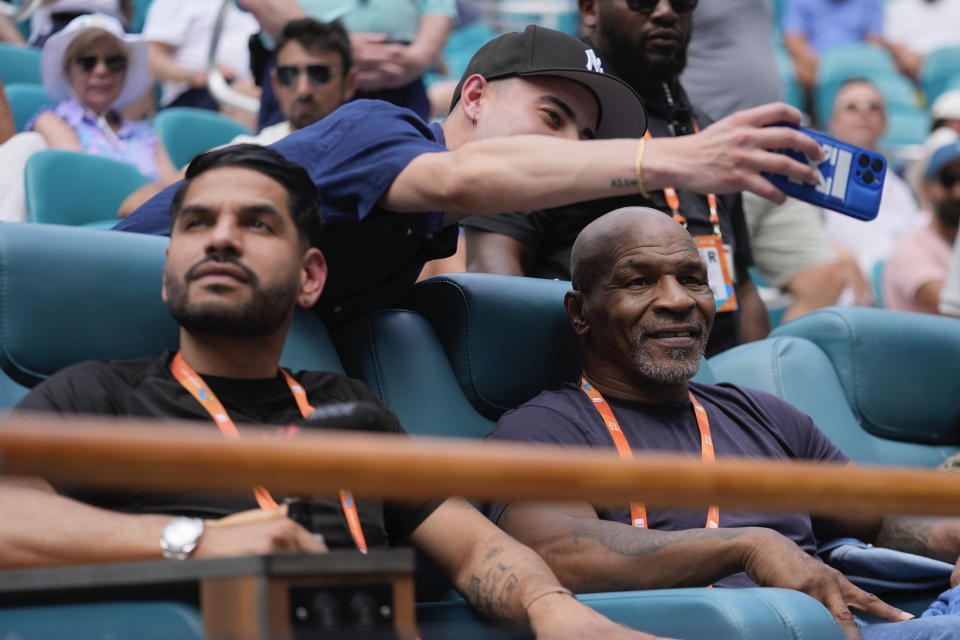 Former boxer Mike Tyson, right, poses for a selfie with a fan between games in a women's singles quarterfinal match between Yulia Putintseva, of Kazakhstan, and Victoria Azarenka, at the Miami Open tennis tournament, Tuesday, March 26, 2024, in Miami Gardens, Fla. (AP Photo/Rebecca Blackwell)