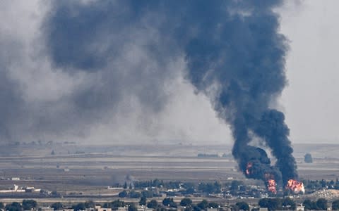 Smoke rises from the Syrian city of Ras al-Ain on Thursday. - Credit: &nbsp;OZAN KOSE/AFP