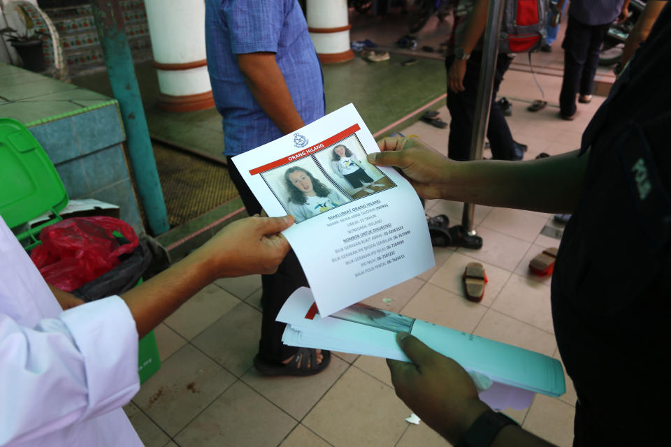A police officer distributes a poster of a missing British girl to a resident after a special prayer at a mosque in Seremban, Negeri Sembilan, Malaysia, Friday, Aug. 9, 2019. Malaysian rescuers played a recording of the voice of the mother of the 15-year-old London girl who mysteriously disappeared from a forest resort, as the search entered a sixth day Friday and her family made an emotional appeal for support. (AP Photo/Lai Seng Sin)