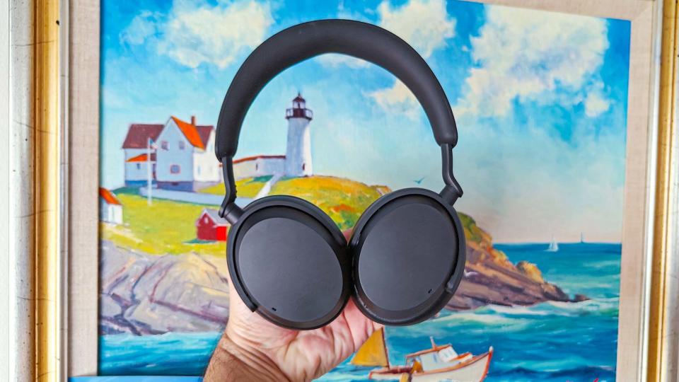 Sennheiser Accentum headphones held up in front of a painting