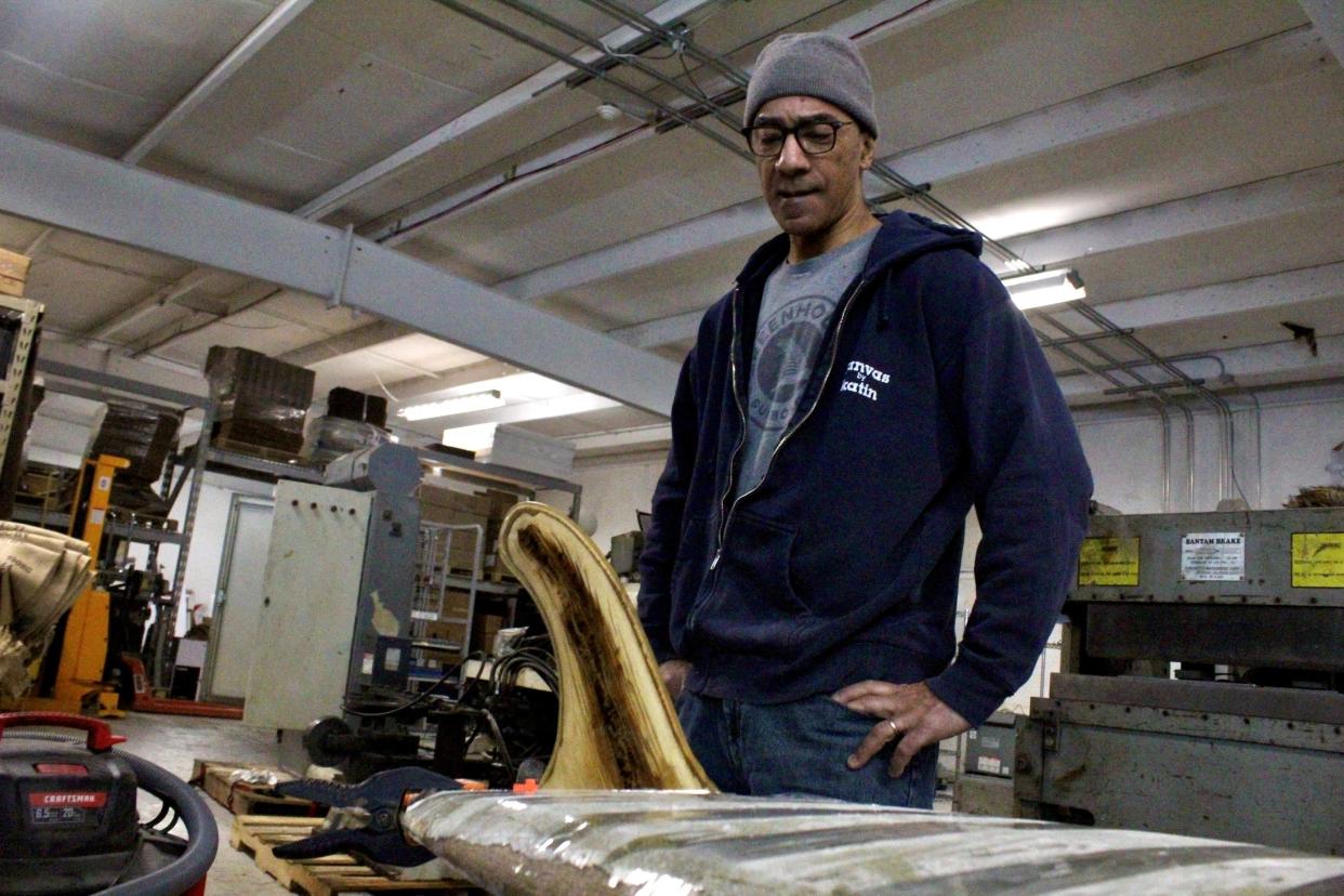 Ken Cole stands over a surfboard he spent five years trying to create using sustainable materials such as Colectivo coffee bags and resin. Cole, a Wisconsin surfer, used to shape boards.