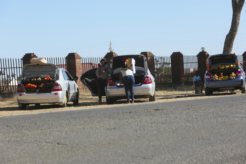 People sell various goods by the side of a busy road in Harare, Zimbabwe, Wednesday, July 1, 2020. Cars have become mobile markets in Zimbabwe where enterprising residents are selling goods from their vehicles to cope with economic hardships caused by the coronavirus. With their car doors and trunks wide open by the side of busy roads, eager sellers display a colorful array of goods in Harare, the capital. (AP Photo/Tsvangirayi Mukwazhi)