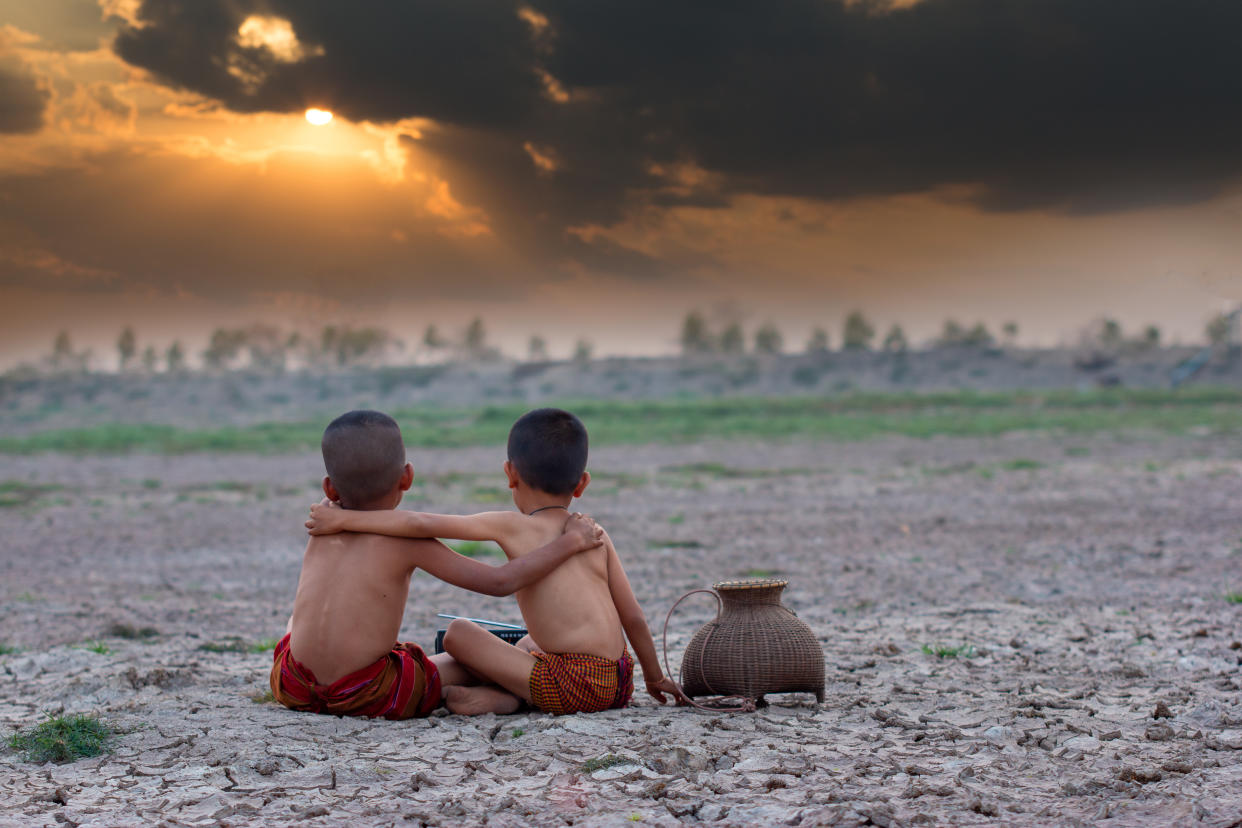 Sad a boy with friend sitting on dry ground.Concept hope and drought.Asia.