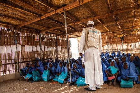 UNICEF education specialist Yusef Ismail talks to pupils at a class at a primary school in Muna Garage IDP camp, Maiduguri, Nigeria November 7, 2016. UNICEF/Naftalin/Handout via REUTERS