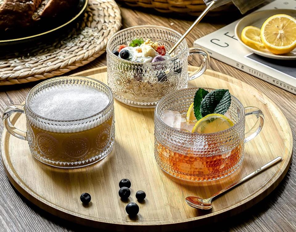 three glass mugs holding drinks and yogurt on a wooden tray