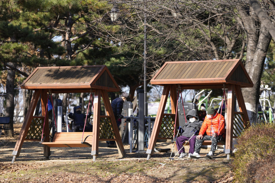 Visitors wearing face masks as a precaution against the coronavirus, rest at a park in Goyang, South Korea, Saturday, Dec. 4, 2021. South Korea again broke its daily records for coronavirus infections and deaths and confirmed three more cases of the new omicron variant as officials scramble to tighten social distancing and border controls. (AP Photo/Lee Jin-man)