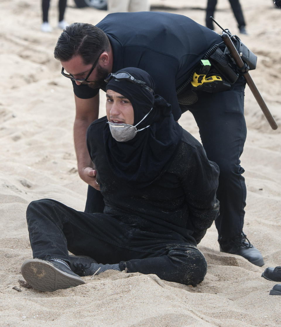 An anti-President Donald Trump protester is taken into custody at a pro-Trump march in Huntington Beach, Calif., on Saturday, March 25, 2017. (Mindy Schauer/The Orange County Register via AP)