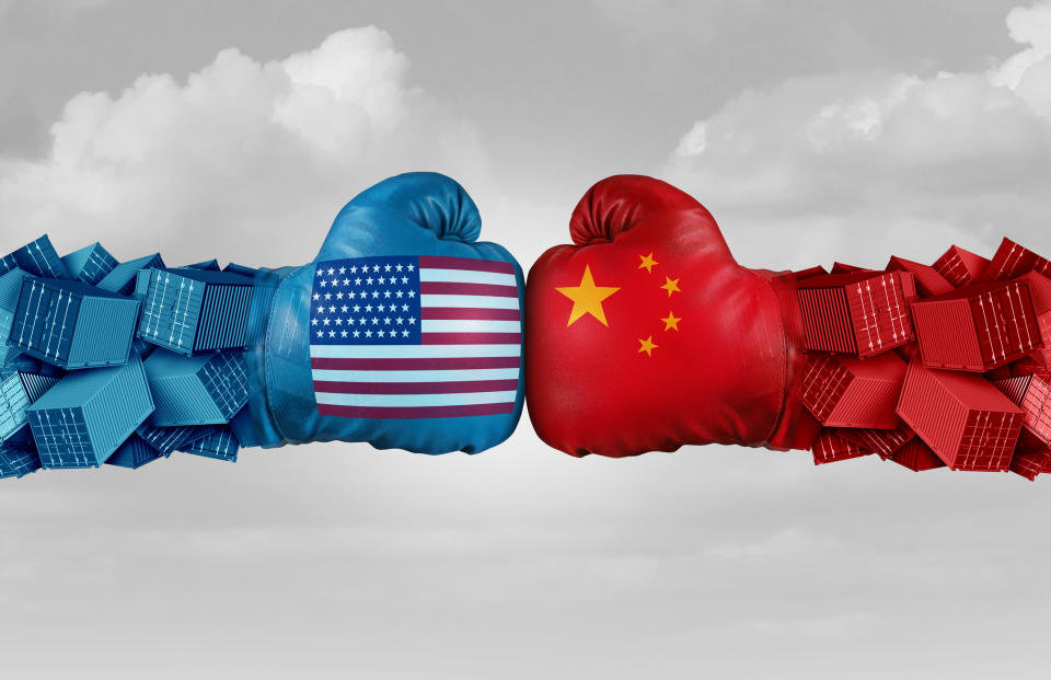 Two boxing gloves, one with the U.S. flag painted on it, one with the China flag painted on it, touch.