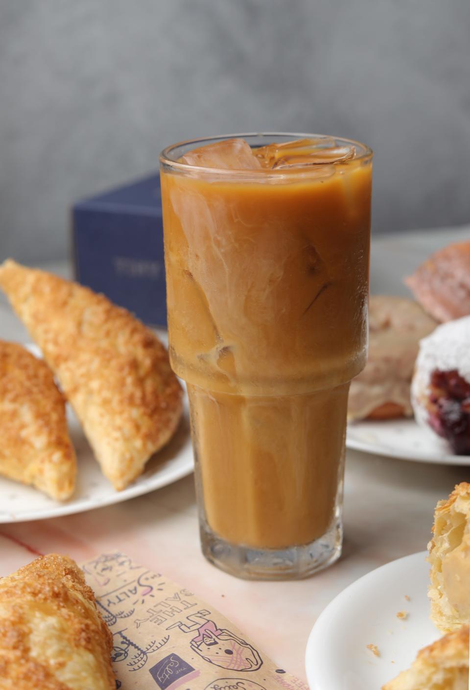 The Salty Donut's Cold Brew Con Leche stands next to a batch of flan pastelitos. Both treats are on a limited-time menu for Hispanic Heritage Month.