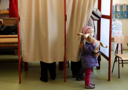 A child stands in front of polling booth as its father votes during Hungarian parliamentary elections at a polling station in Budapest, Hungary April 8, 2018. REUTERS/Bernadett Szabo