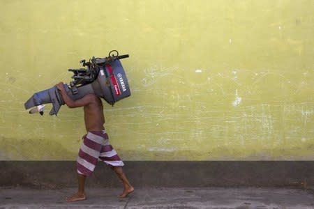 A man carries an outboard motor which he found and recovered from the seabed in Rio Caribe, a town near caribbean islands, in the eastern state of Sucre, Venezuela October 29, 2015. REUTERS/Carlos Garcia Rawlins