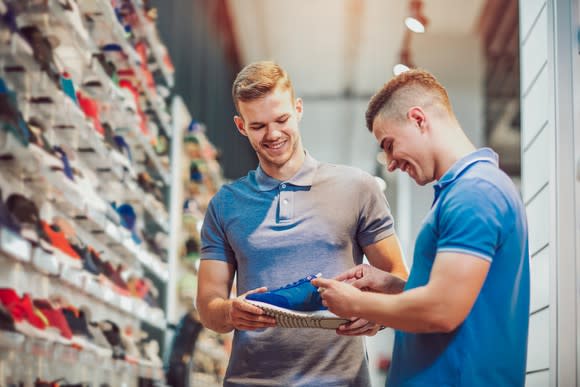 Store clerk helping a consumer look at athletic shoes