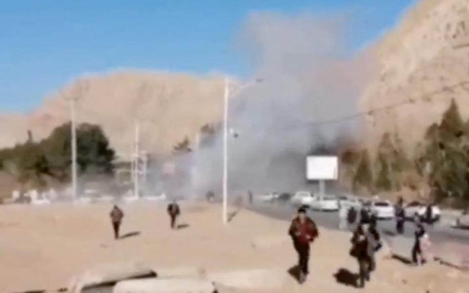 People run as smoke rises, amid local media reports of explosions during a ceremony held to mark the death of late Iranian General Qassem Soleimani, in Kerman, Iran