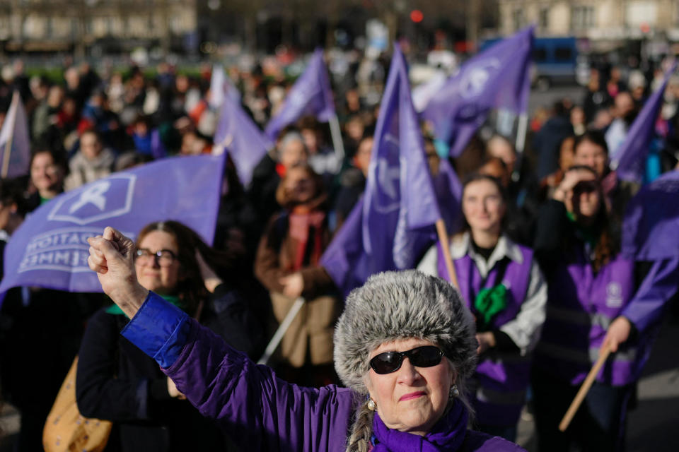 A woman clenches her fist and others hold flags of the