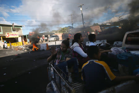 People pass next to burning tires as supporters of presidential candidate Salvador Nasralla take part during a protest caused by the delayed vote count for the presidential election at Villanueva neighborhood in Tegucigalpa, Honduras, December 1, 2017. REUTERS/Edgard Garrido