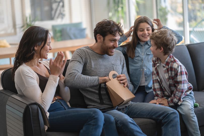 Excited children and mother waiting for daddy to open a present for Father's Day