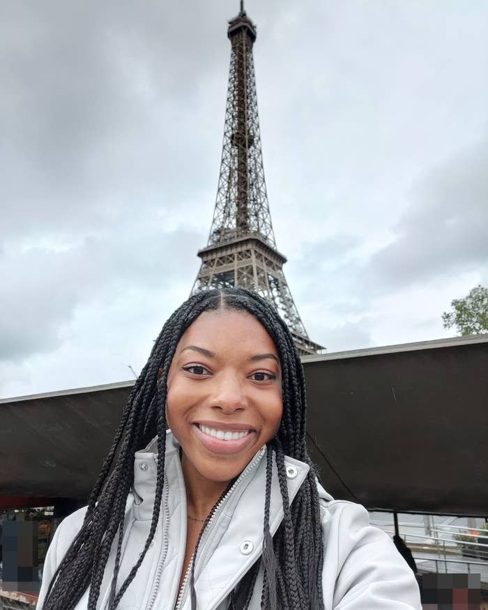 The author smiles for a selfie with the Eiffel Tower in the background