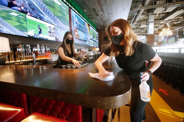 In this photo taken back in February, staff at Browns Socialhouse in Winnipeg clean up the bar area before the arrival of customers. Manitoba has put its reopening plans on hold and extended restrictions due to its third wave of COVID-19.