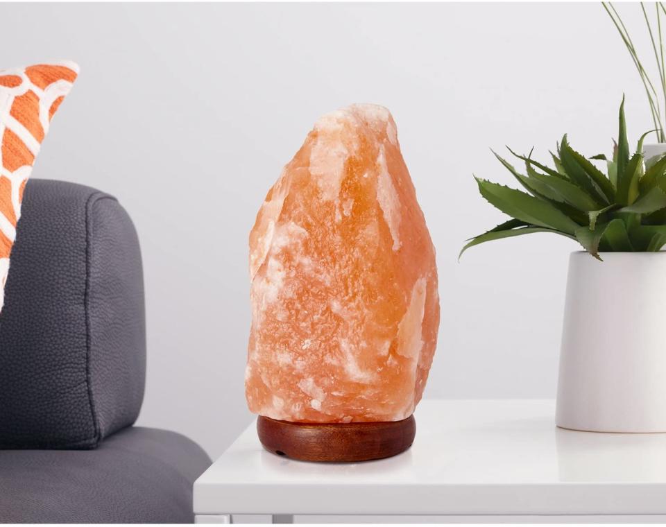 Himalayan smart lamp next to a potted plant on a white side table.