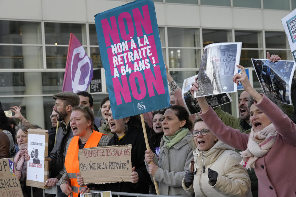 Demonstrators, one holding a placard which reads "No to Retirement at 64", shout slogans as French President Emmanuel Macron leaves after explaining his vision on the future of Europe in a lecture in The Hague, Netherlands, Tuesday, April 11, 2023. (AP Photo/Peter Dejong)