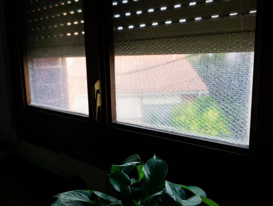 Looking out at bubble-wrapped windows from inside a dark house.