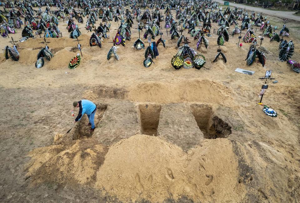 A gravedigger prepares the ground for a funeral at a cemetery in Irpin, Ukraine, on April 21, 2022. The first several rows contain people killed during the Russian occupation of the area.