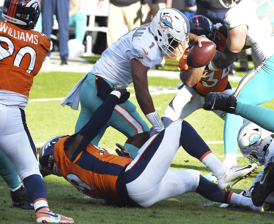 Denver Broncos linebacker Malik Reed, bottom, sacks Miami Dolphins quarterback Tua Tagovailoa, top, in the first half of an NFL football game in Denver, Sunday, Nov. 22, 2020. (Jerilee Bennett/The Gazette via AP)