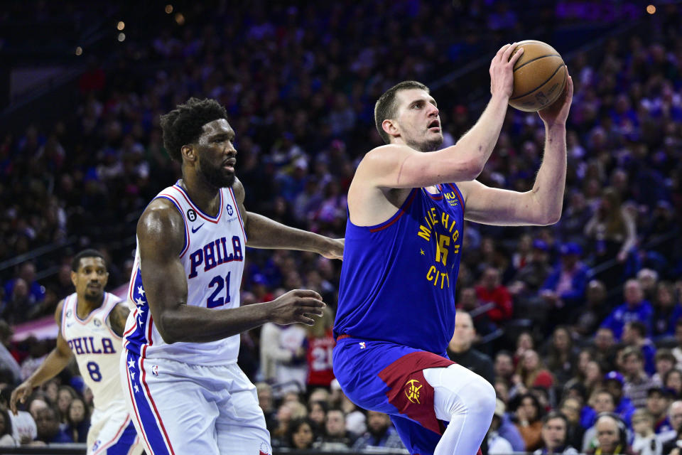 Denver Nuggets' Nikola Jokic, right, looks to the basket as he gets past Philadelphia 76ers' Joel Embiid (21) during the first half of an NBA basketball game, Saturday, Jan. 28, 2023, in Philadelphia. (AP Photo/Derik Hamilton)