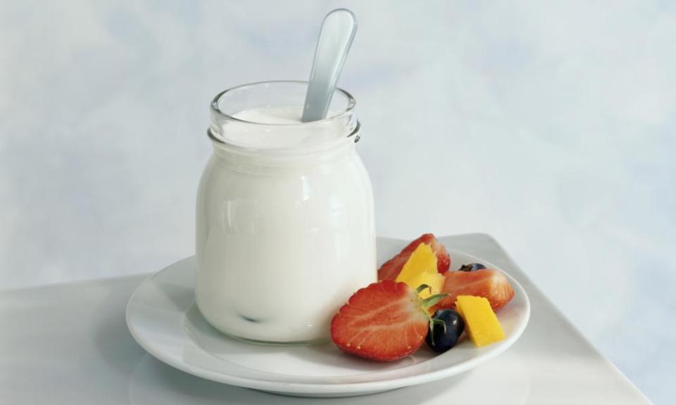 Jar of yoghurt and freshly cut fruit on plate, close-up