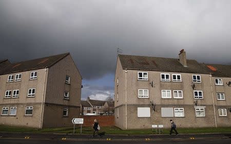 Pedestrians walk past a row of flats across from the former site of the Johnnie Walker distillery in Kilmarnock, Scotland March 25, 2014. REUTERS/Suzanne Plunkett