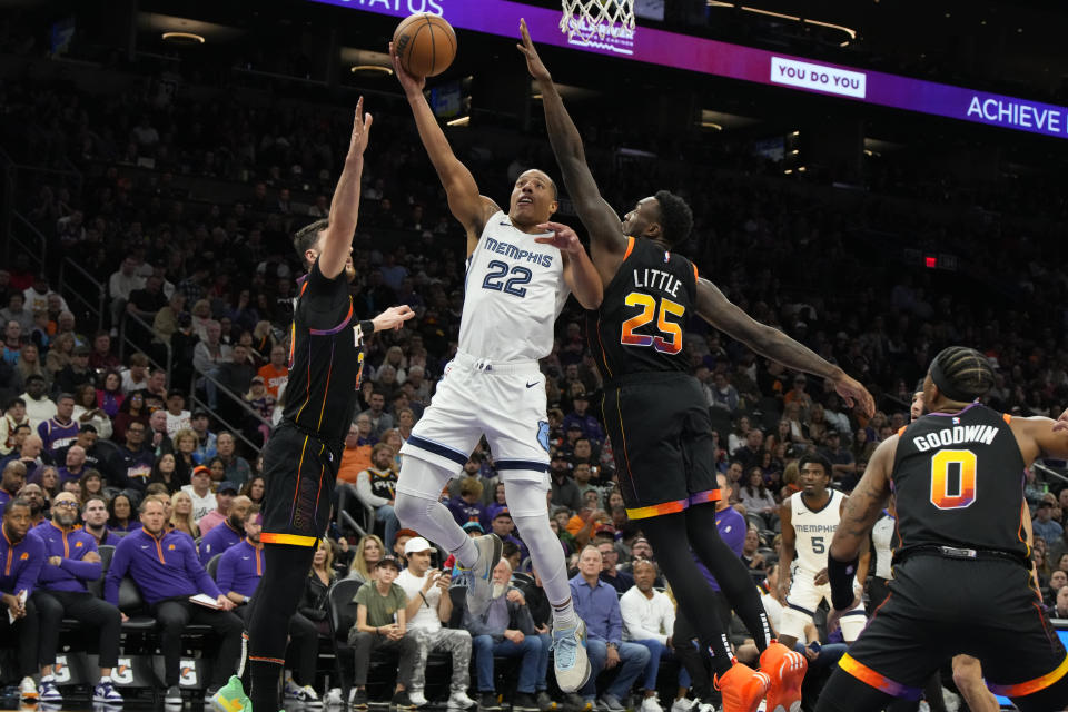 Memphis Grizzlies guard Desmond Bane (22) drives between Phoenix Suns center Jusuf Nurkic and forward Nassir Little (25) during the first half of an NBA basketball game, Saturday, Dec. 2, 2023, in Phoenix. (AP Photo/Rick Scuteri)