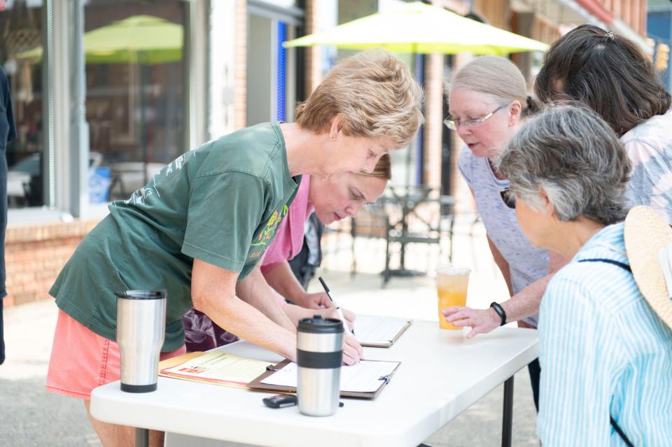 Marshall residents Claire Hammer and Sarah Simmons sign a petition seeking a city-wide vote on the Marshall Megasite rezoning on Tuesday, May 23, 2023 in downtown Marshall.
