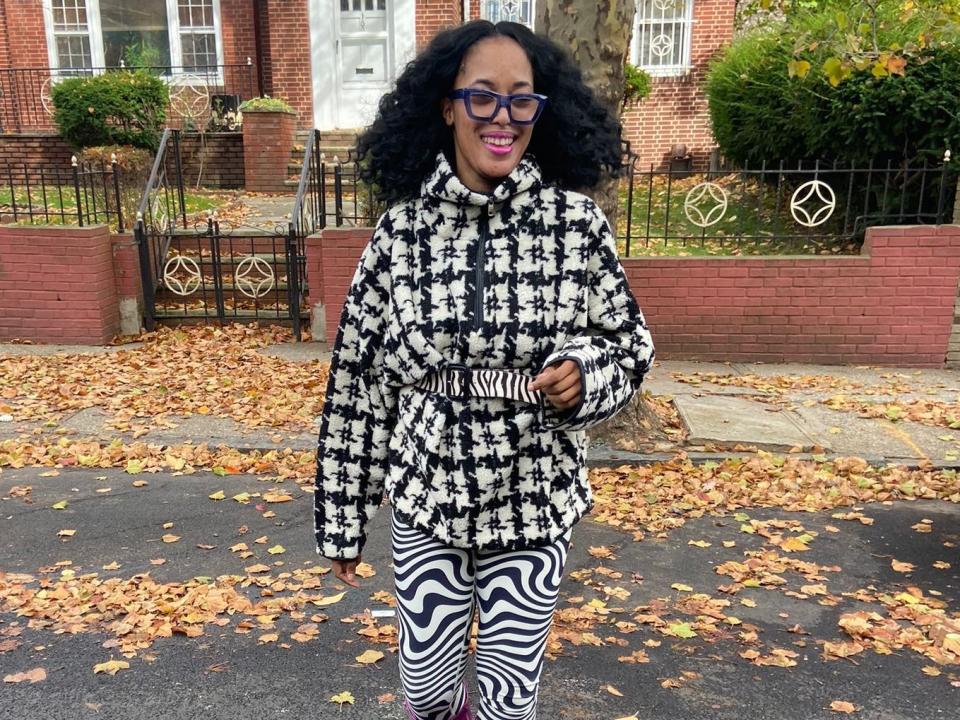 Sandra outside wearing houndstooth sweater with black and white leggings and pink boots