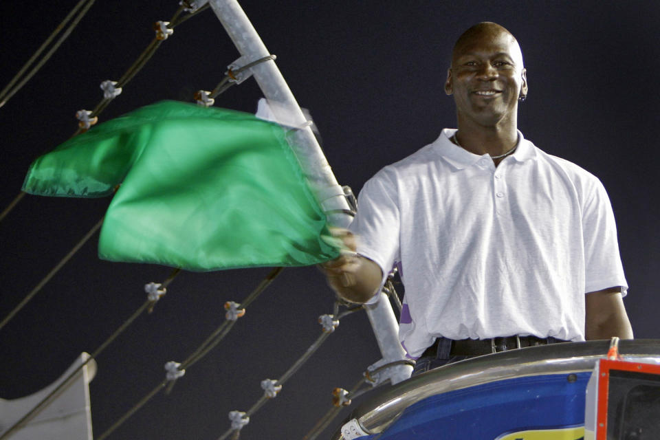 FILE - In this May 22, 2010, file photo, Charlotte Bobcats owner Michael Jordan practices waving the green flag before a NASCAR All-Star auto race at Charlotte Motor Speedway in Concord, N.C. NASCAR needs to roll out the red carpet when the Daytona 500 opens the season Sunday. Michael Jordan and the rapper Pitbull, racing’s newest team owners, are expected to attend.  (AP Photo/Chuck Burton, File)