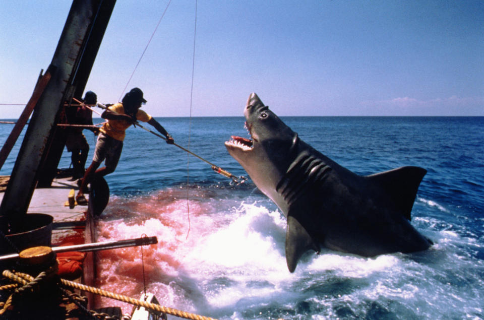 A shark diving out of the water towards a boat