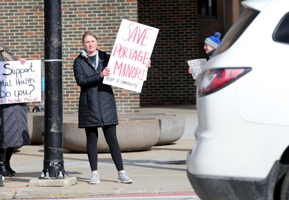 People stand along Lafayette Boulevard with signs Tuesday, March 14, 2023, at the County-City Building in downtown South Bend. About a dozen people hold signs seeking a delay in the decision by county officials to decide the fate of Portage Manor in South Bend.
