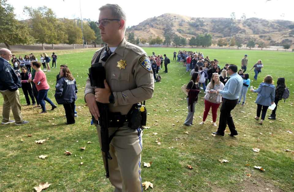 A police officer stands guard as students wait to reunite with their parents following a shooting at Saugus High School that injured several people, Nov. 14, 2019, in Santa Clarita, Calif. (Photo: Ringo H.W. Chiu/AP)