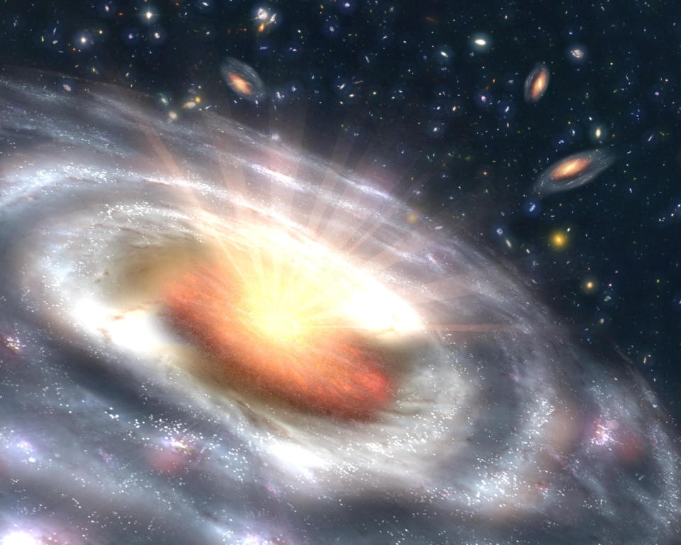 a swirling galaxy throws out yellow rays towards the blackness of space filled with other smaller galaxies above.