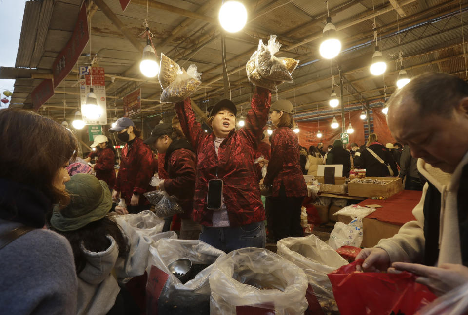 A sales woman shouts at the customers to buy as they go shopping for the upcoming Lunar New Year celebrations at the Dihua street market in Taipei, Taiwan, Thursday, Feb. 8, 2024. Taiwanese shoppers started hunting for delicacies, dried goods and other bargains at the market ahead of the Lunar New Year celebrations which fall on Feb. 10 this year. (AP Photo/Chiang Ying-ying)