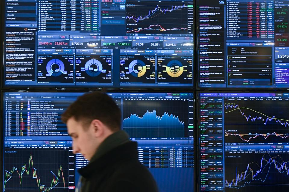 A trader walks past a display showing financial data at the offices of CMC Markets in the City of London. Photo: Daniel Sorabji/AFP/Getty Images