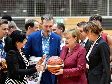 German Chancellor Angela Merkel holds a basketball as she meets with a local basketball team in Chemnitz, Germany November 16, 2018. REUTERS/Matthias Rietschel