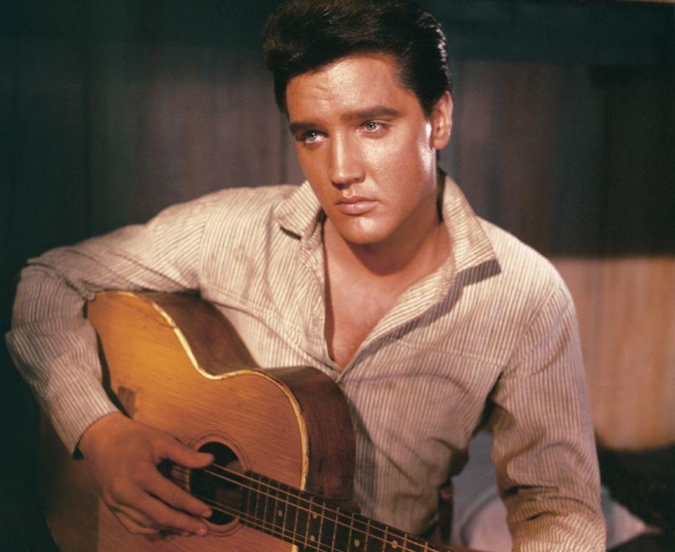 A portrait of American singer and actor Elvis Presley holding an acoustic guitar circa 1956