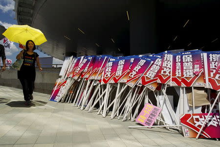 A pro-democracy protester carrying a yellow umbrella, symbol of the Occupy Central movement, walks past placards which read "support electoral reform", belonging to pro-China supporters, outside Legislative Council in Hong Kong, China June 17, 2015. REUTERS/Liau Chung-ren