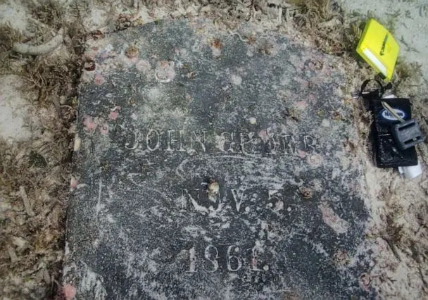 PHOTO: A gravestone with sand shows the inscription &#39;John Greer. Nov. 5. 1861.&#39; (NPS Photo by C. Sproul)