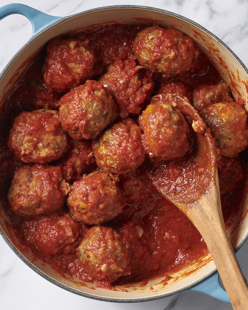 meatballs in dutch oven with wooden spoon