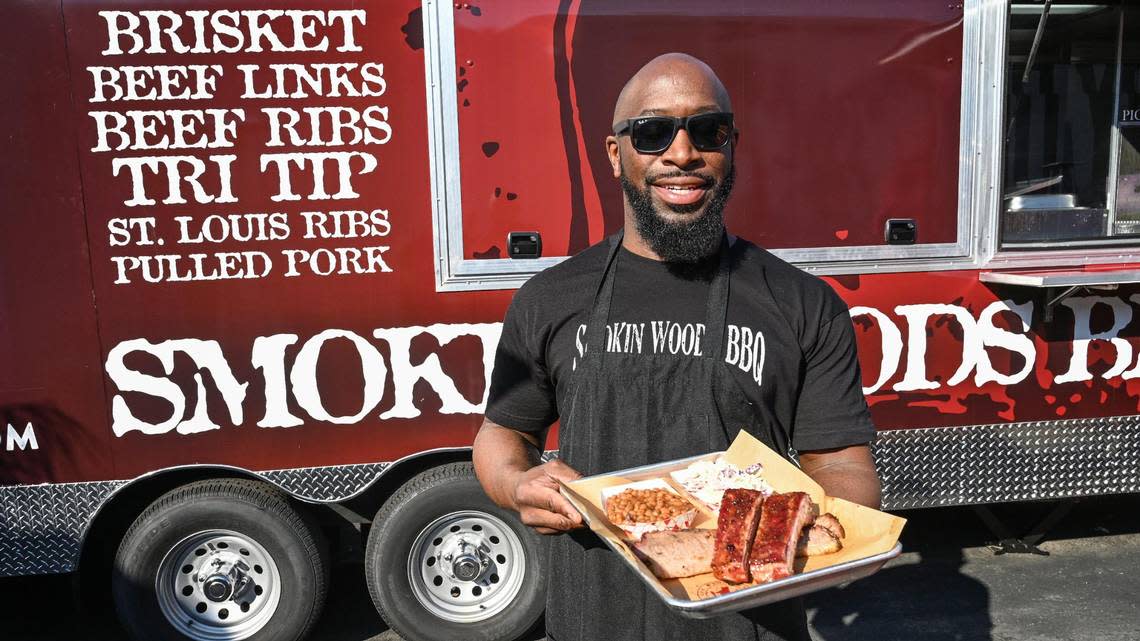 James Woodard stands with a plate of barbecue and sides outside his Smoking Woods food truck in Fresno’s Brewery District in downtown Fresno on Friday, Dec. 9, 2022.