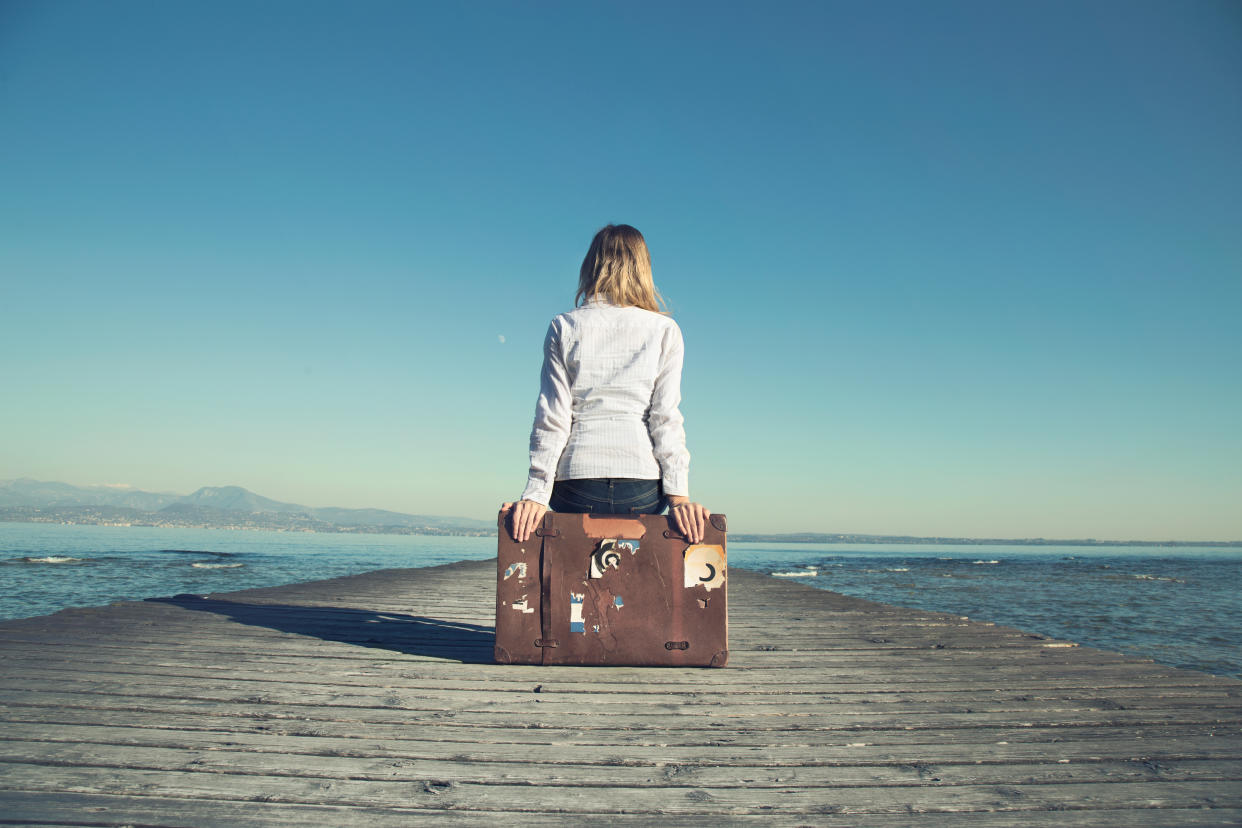 woman sitting on her suitcase waiting for the sunset in a spectacular view