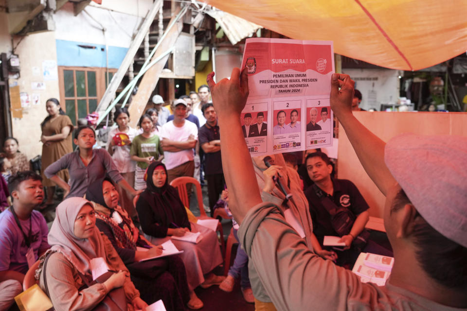 An electoral worker holds up a ballot during the vote counting at a polling station following the election in Jakarta, Indonesia, Wednesday, Feb. 14, 2024. Indonesian voters were choosing a new president Wednesday as the world's third-largest democracy aspires to become a global economic powerhouse a quarter-century after shaking off a brutal dictatorship. (AP Photo/Tatan Syuflana)