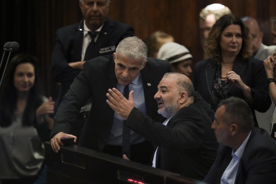 Israeli Foreign Minister Yair Lapid, center, speaks with lawmaker Mansour Abbas ahead of the vote on a bill to dissolve parliament at the Knesset, Israel's parliament, in Jerusalem, Thursday, June 30, 2022. Lapid will serve as caretaker prime minister until elections this fall. It would be Israel's fifth election in under four years. (AP Photo/Ariel Schalit)