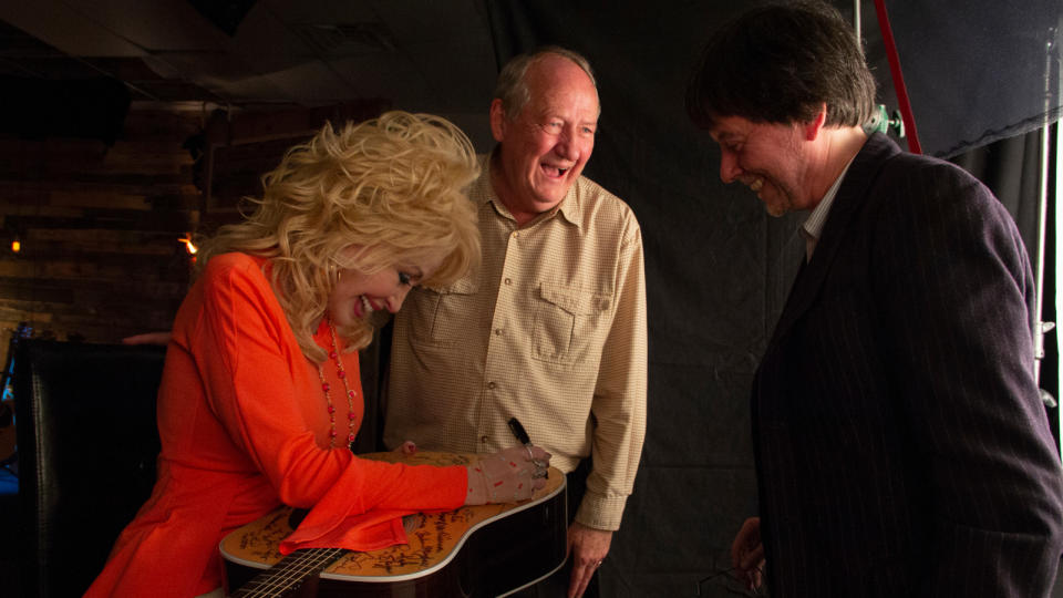 Dolly Parton, with Dayton Duncan (center)  and Ken Burns, signs one of the Martin  guitars provided for Country Music.